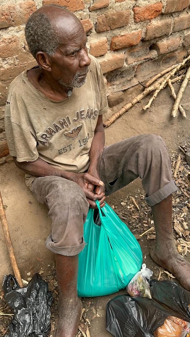 Elderly man with a disability receiving relief support at home in Kawempe